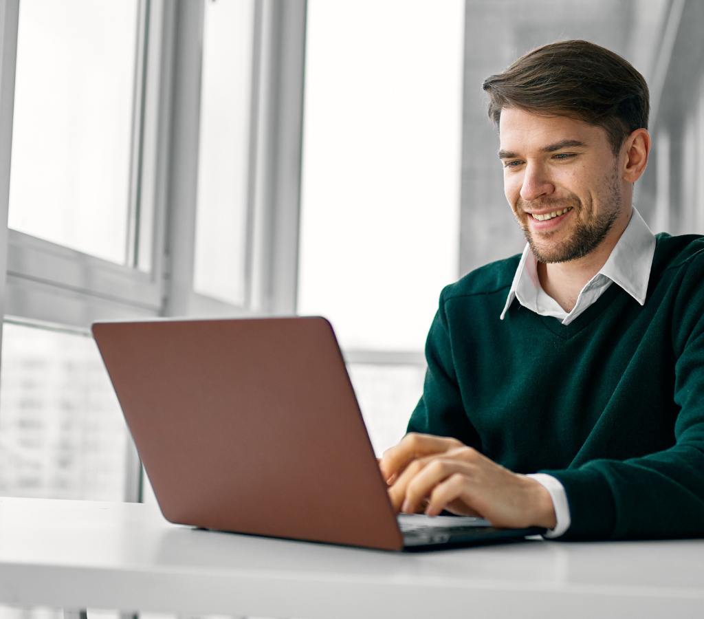 A professional sitting at a desk with a laptop and a cup of coffee, looking at a job interview follow-up email on the screen